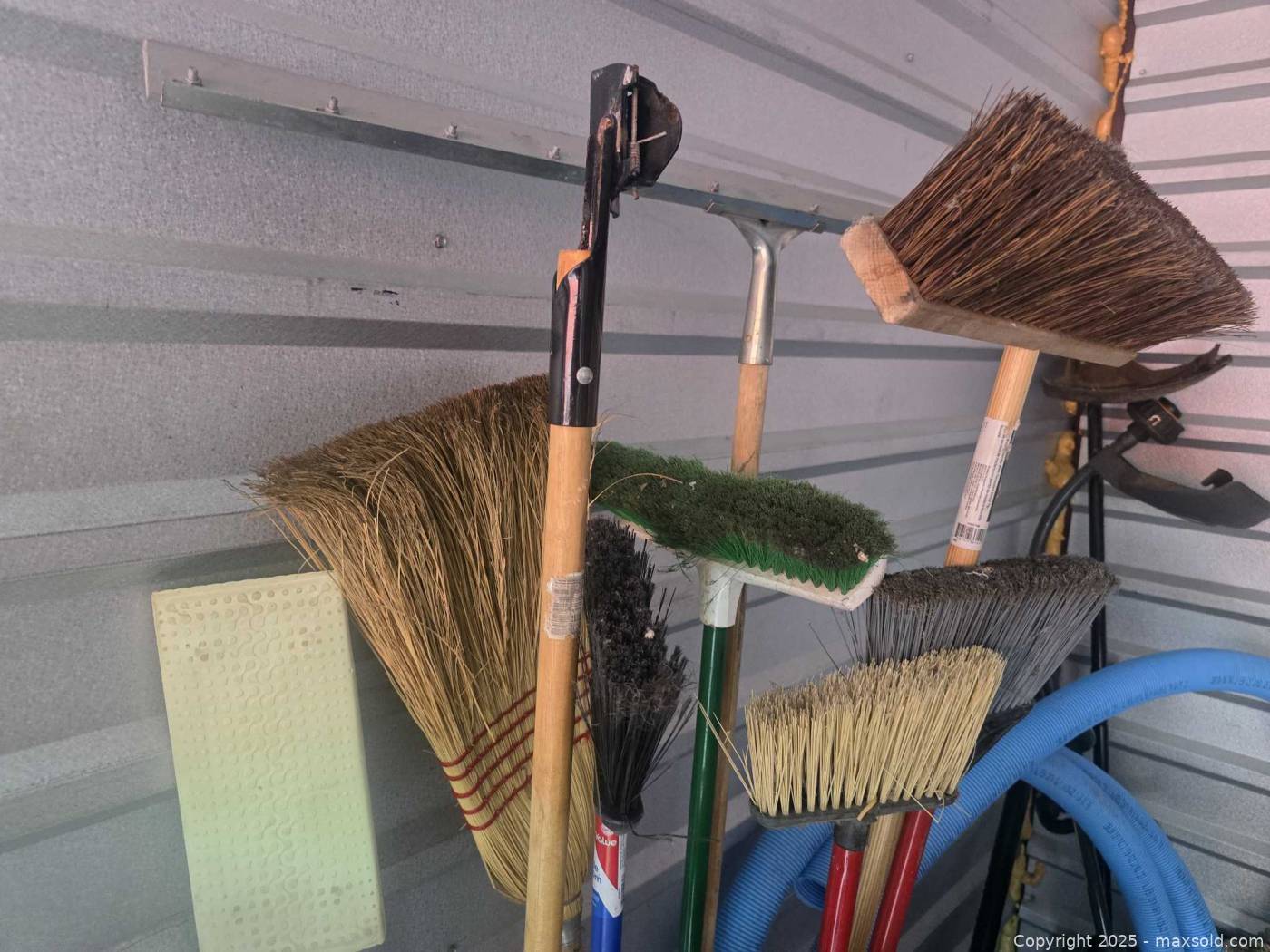 Heavy duty corner storage rack with assorted brooms and cleaning tools ...