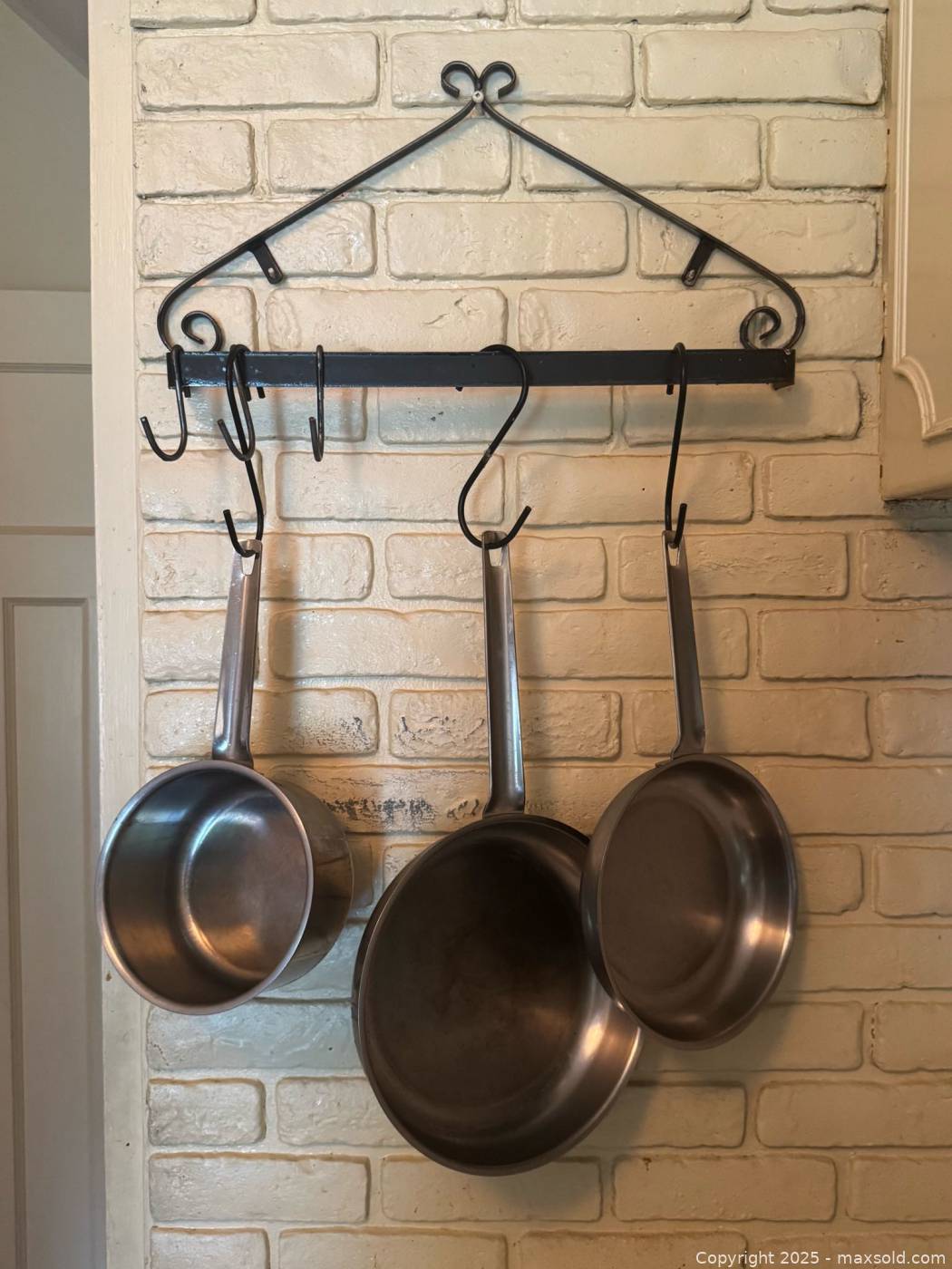 Wall-mounted wrought iron pan rack with 3 stainless steel pans | Maxsold